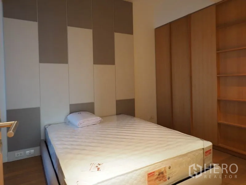 Condominium for rent in Yan Nawa, Bangkok - Cozy bedroom with padded feature wall, large wardrobe and timber flooring.
