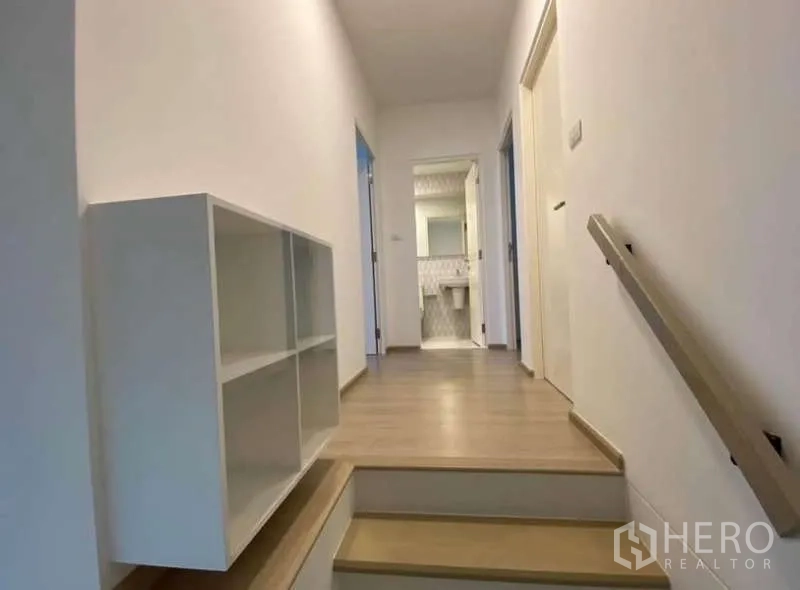 Townhouse for rent in Bang Phli, Samut Prakan - Upstairs hallway with built-in shelving leading to bedrooms and bathroom.