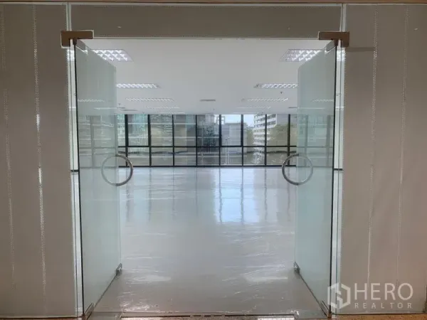 办公空间 出租在Bang Rak, Bangkok - 玻璃双开门通向明亮的开放式办公室，地面光洁，前方为整面窗。