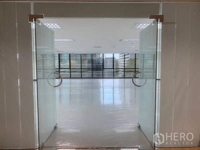 办公空间 出租在Bang Rak, Bangkok - 玻璃双开门通向明亮的开放式办公室，地面光洁，前方为整面窗。