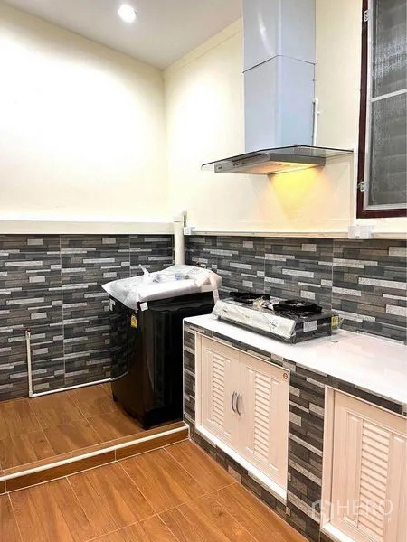 联排别墅 出租在Bang Na, Bangkok - 厨房角落设排油烟机、燃气灶、砖纹挡水板及家务区。