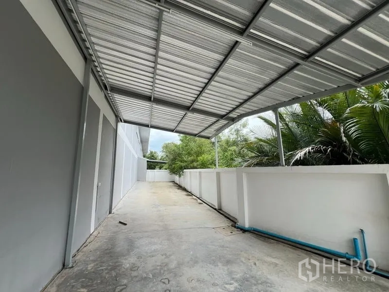 โรงงาน ให้เช่าในPhra Samut Chedi, Samut Prakan - ลานข้างอาคารมีหลังคาเมทัลชีท ทางเดินคอนกรีต และท่อสาธารณูปโภค