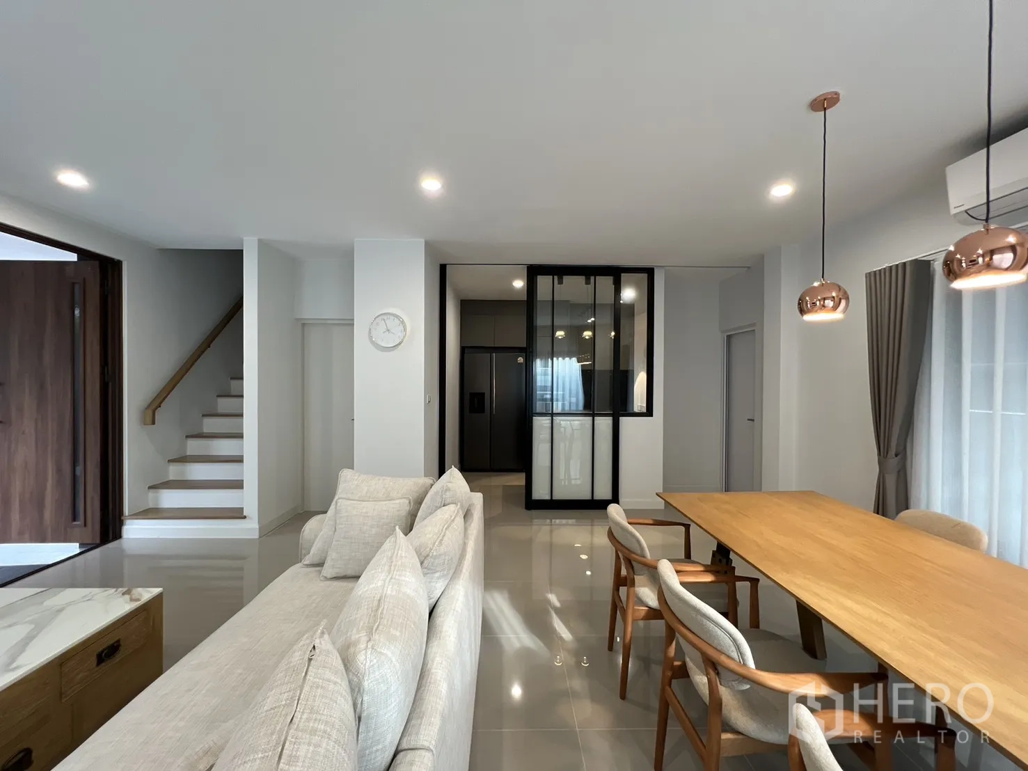 Detached House for rent in Prawet, Bangkok - Open-plan lounge with staircase and glass-partitioned kitchen.