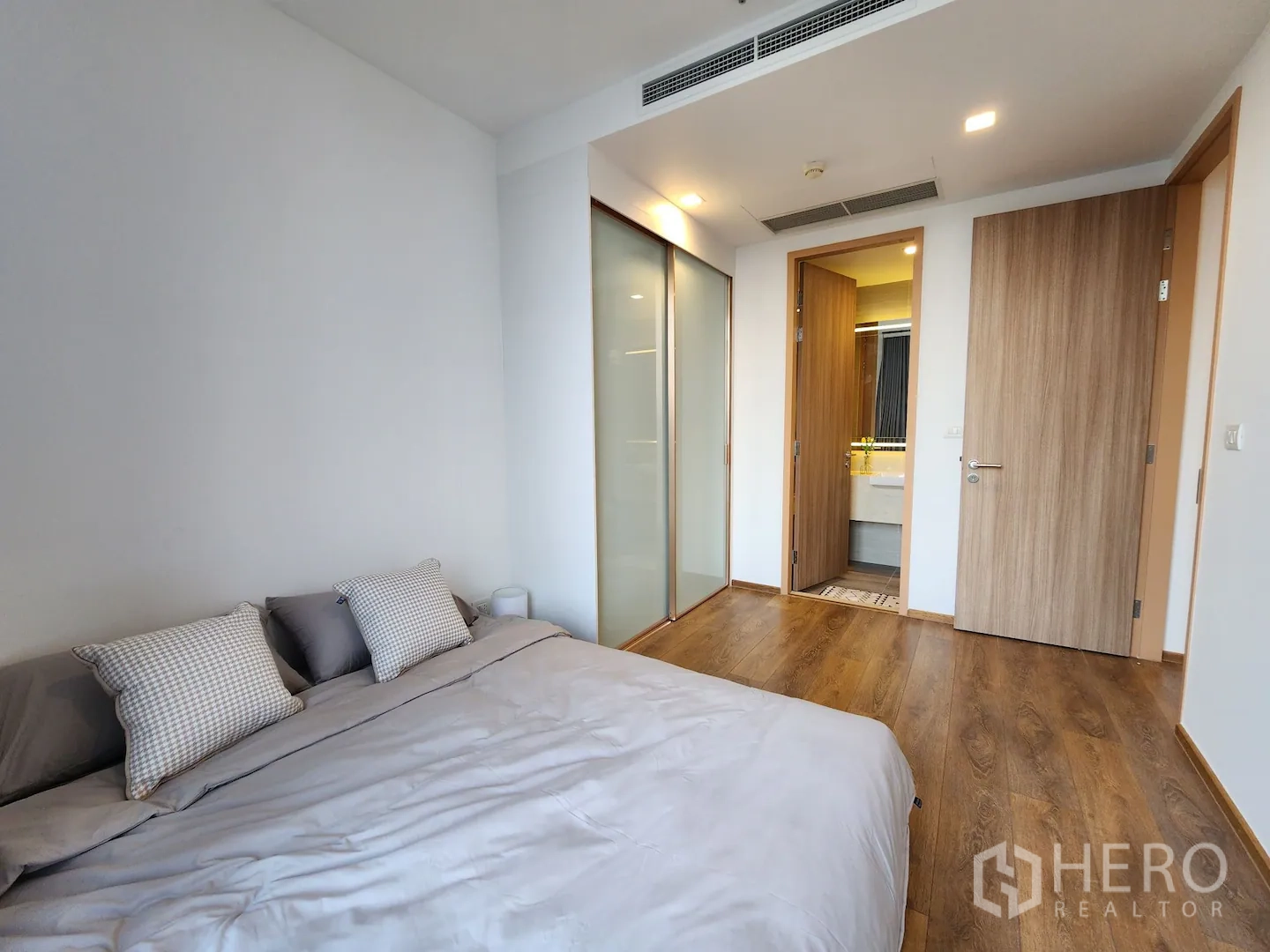 คอนโด for rent in Watthana, Bangkok - ห้องนอนหลักพื้นไม้ ตู้เสื้อผ้าบานเลื่อน และทางเข้าห้องน้ำดีไซน์โมเดิร์น ในคอนโดเขตวัฒนา กรุงเทพฯ