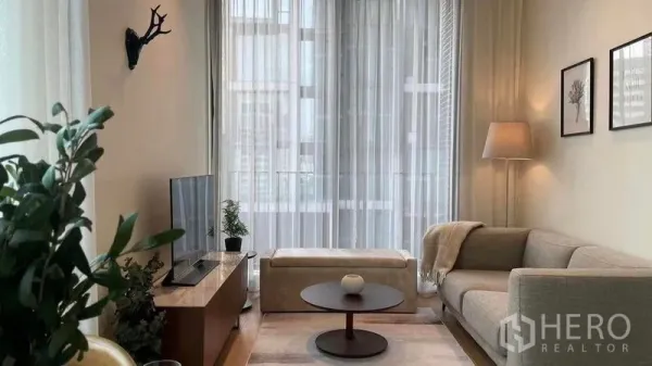 公寓 出租在Pathum Wan, Bangkok - 采光充足的客厅，布艺沙发、圆茶几与纱帘，外接城市景