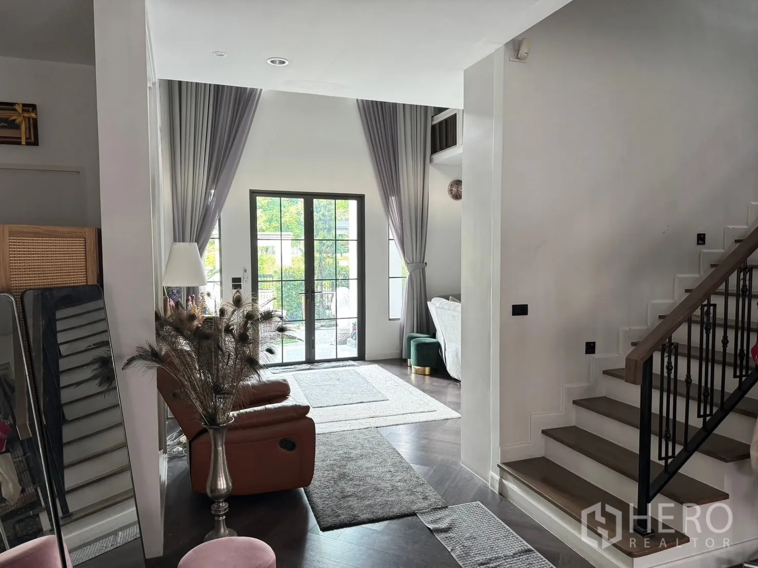 独立式住宅 出售在Mueang Pathum Thani, Pathum Thani - 开放起居区带楼梯，高窗帘与法式玻璃门通向花园。