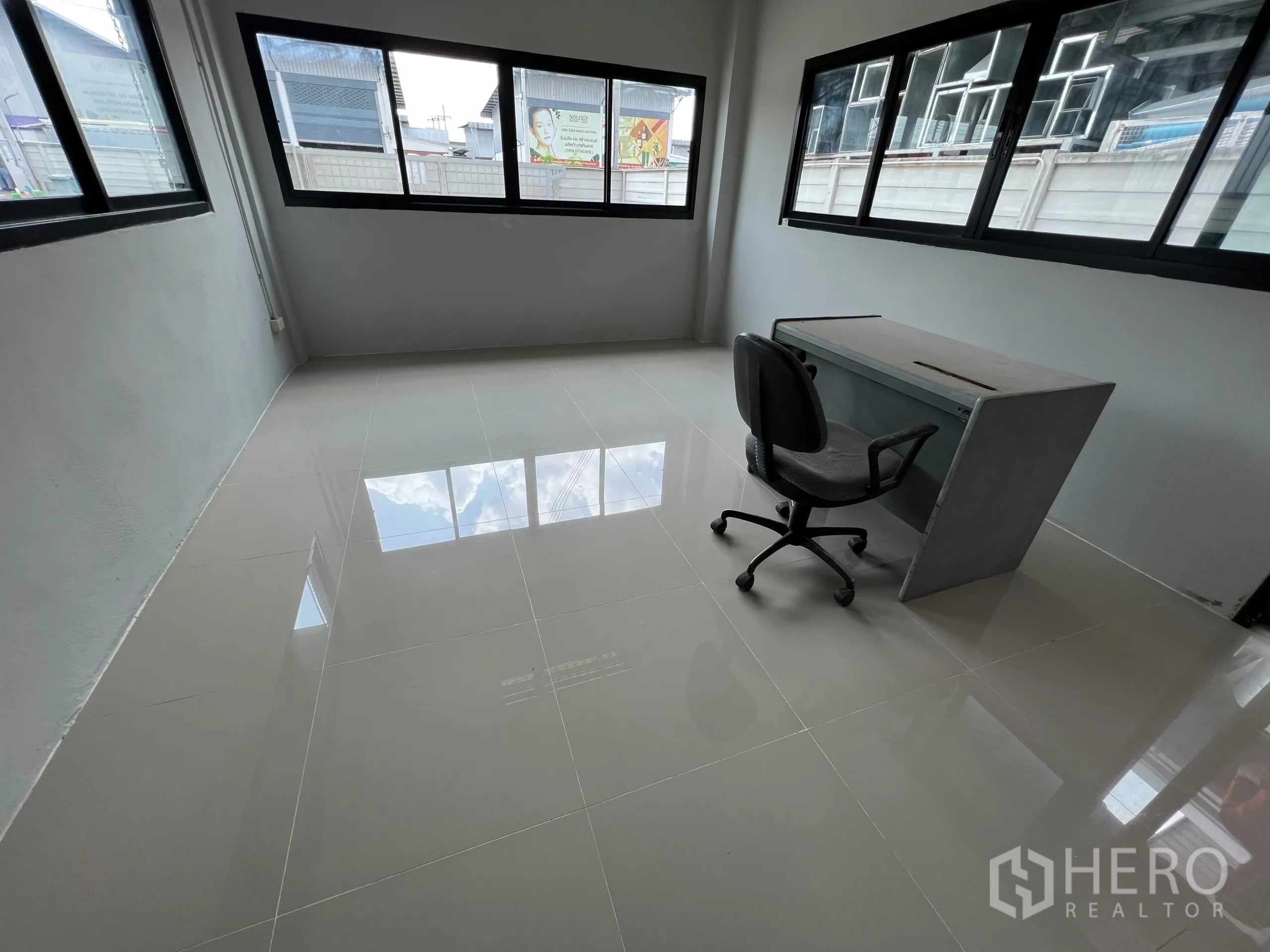 Warehouse for sale in Bang Len, Nakhon Pathom - Bright office room with tiled floor, corner windows and a desk chair.