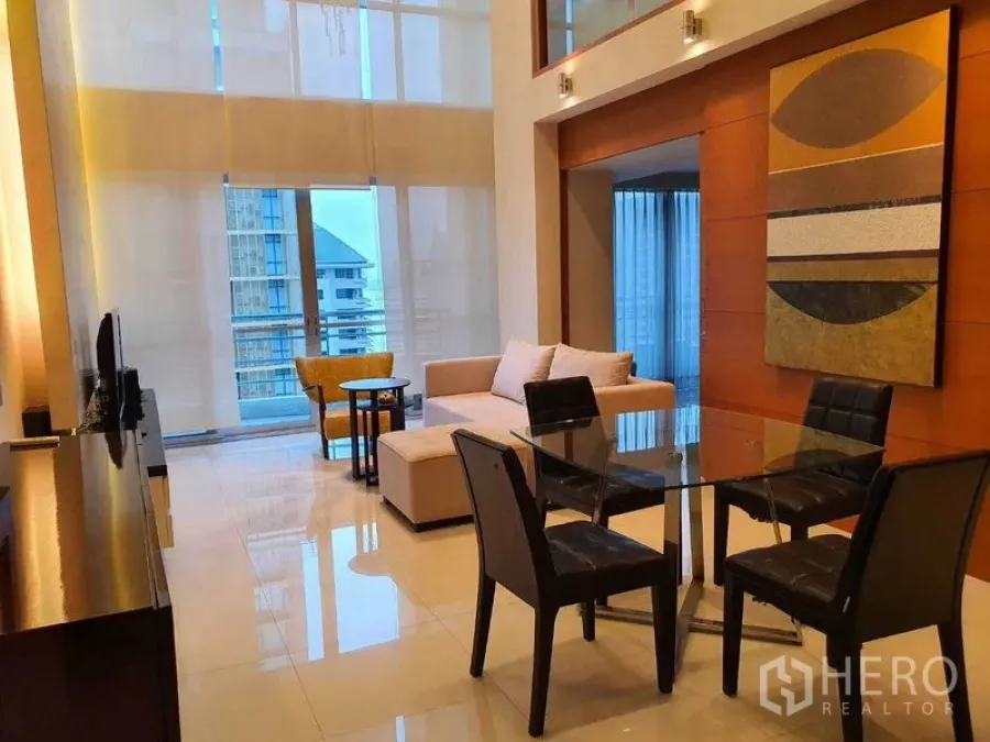 คอนโด ให้เช่าในPathum Wan, Bangkok - ห้องนั่งเล่น–ทานอาหารเพดานสูงสองชั้น โต๊ะกระจก โซฟา และทางออกระเบียง