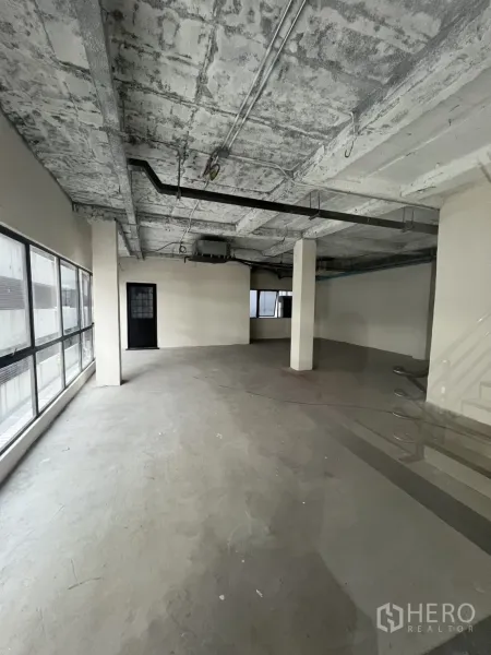 零售空间 出租在Watthana, Bangkok - 宽敞毛坯商铺，裸露混凝土顶、居中立柱与整面采光窗。