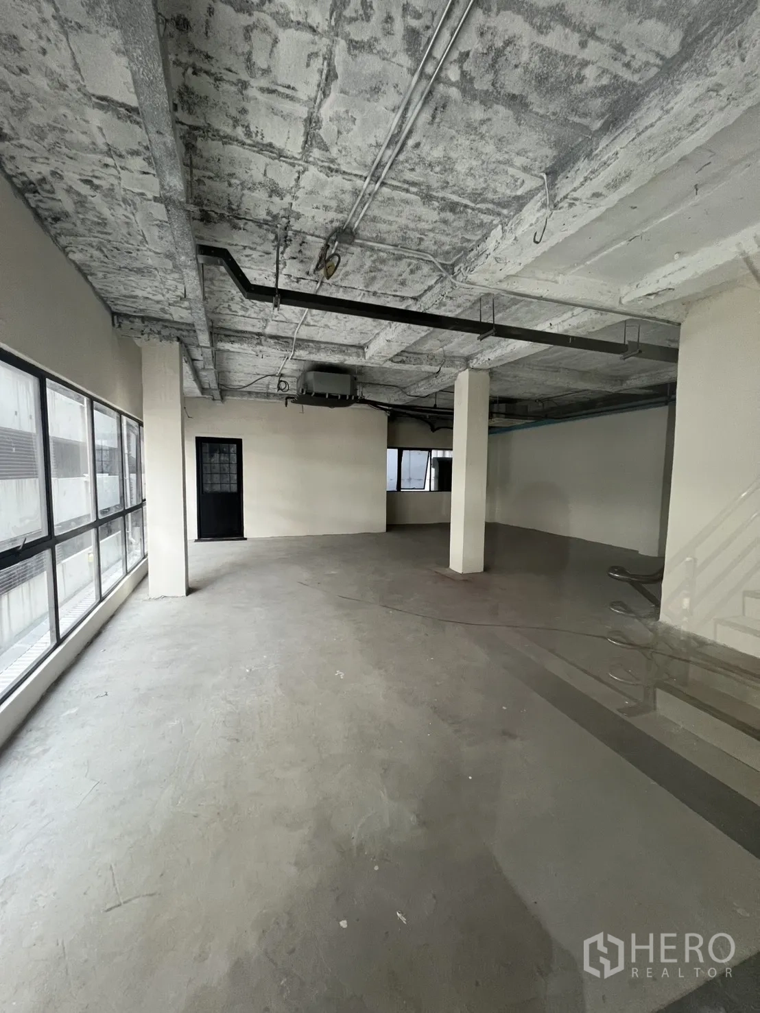 零售空间 出租在Watthana, Bangkok - 宽敞毛坯商铺，裸露混凝土顶、居中立柱与整面采光窗。