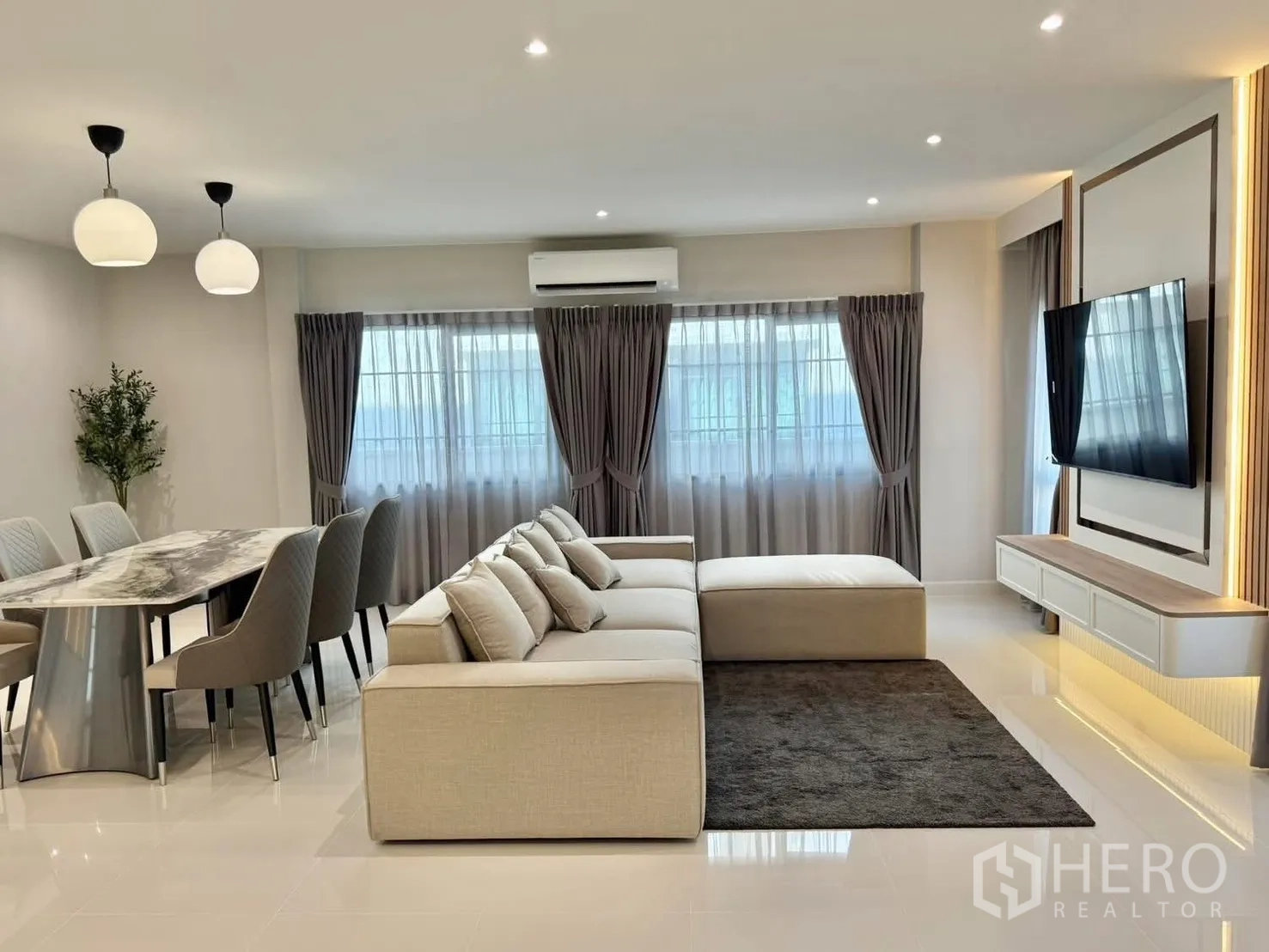 Detached House for rent in Bang Phli, Samut Prakan - Another angle of the living–dining area showing big windows, air conditioner and mounted TV.