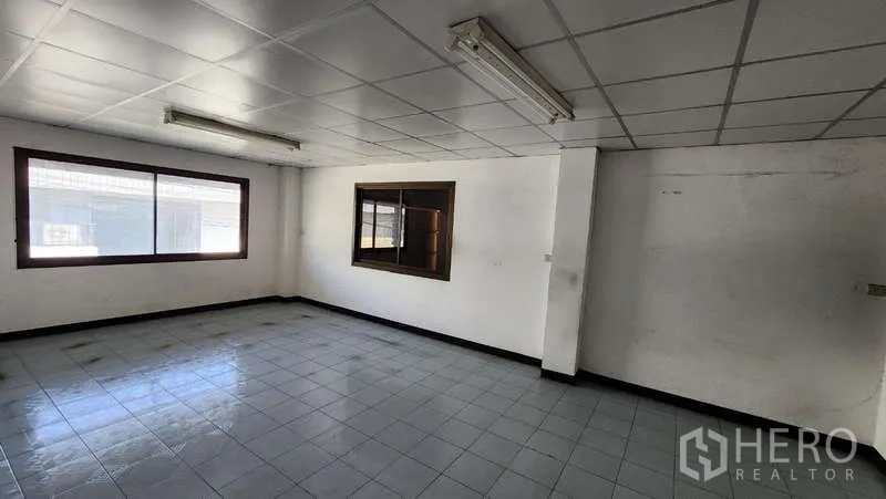 Warehouse for rent in Nong Khaem, Bangkok - Bright upstairs office room with large window, white ceiling tiles, and ceramic floor.