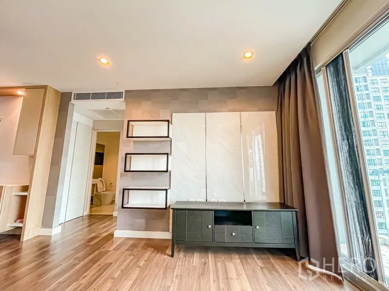 คอนโด ขาย - ผนังทีวีพร้อมชั้นลอยและตู้วางทีวี ตรงข้ามหน้าต่างสูงเต็มบาน