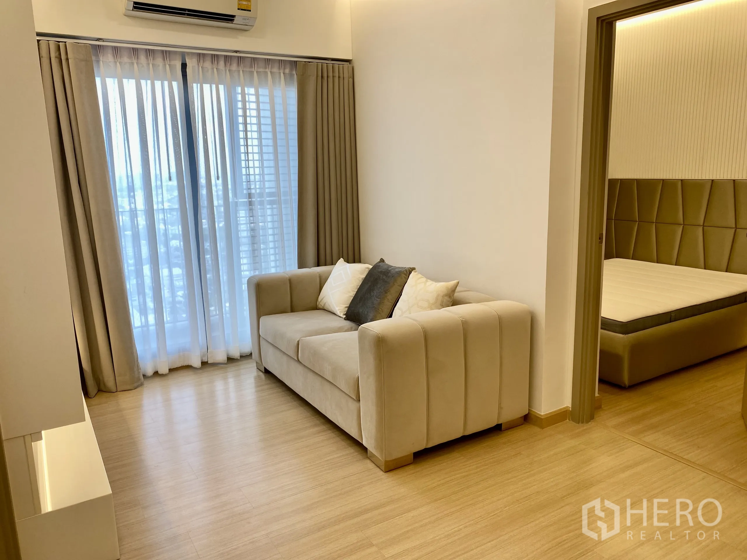 คอนโด ให้เช่าในPhra Khanong, Bangkok - พื้นที่นั่งเล่นหน้าต่างสูงจรดเพดานออกสู่ระเบียง พื้นไม้สีอ่อนและทางเข้าห้องนอน