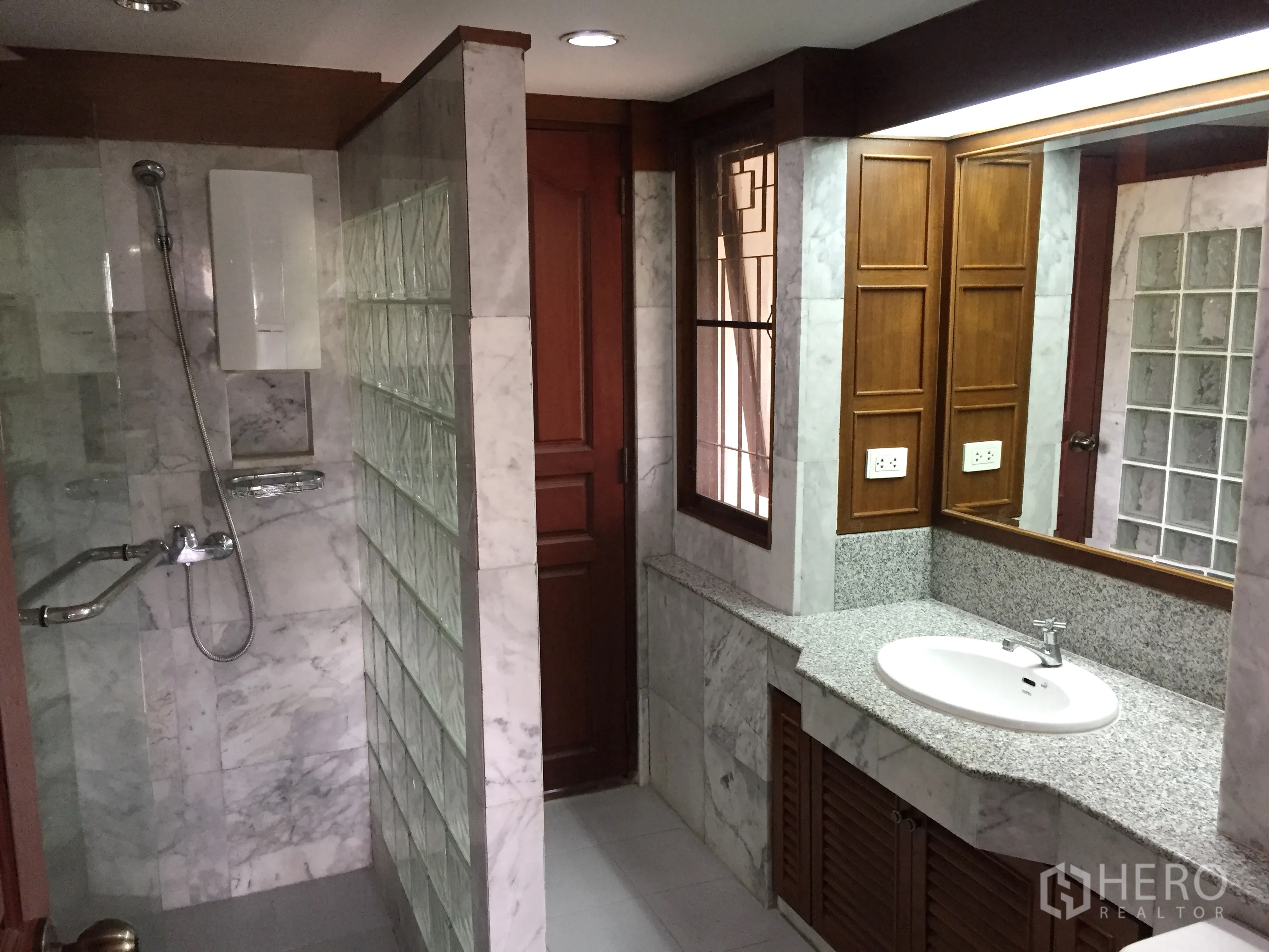 Detached House for rent in Khlong Toei, Bangkok - Bathroom finished in marble with a glass-block shower and long granite vanity.