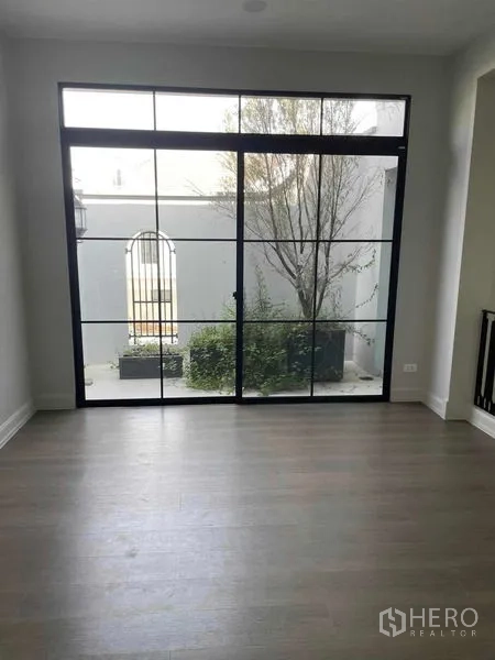 Detached House for sale in Saphan Sung, Bangkok - Family room opening to a private courtyard through black‑framed glass doors.