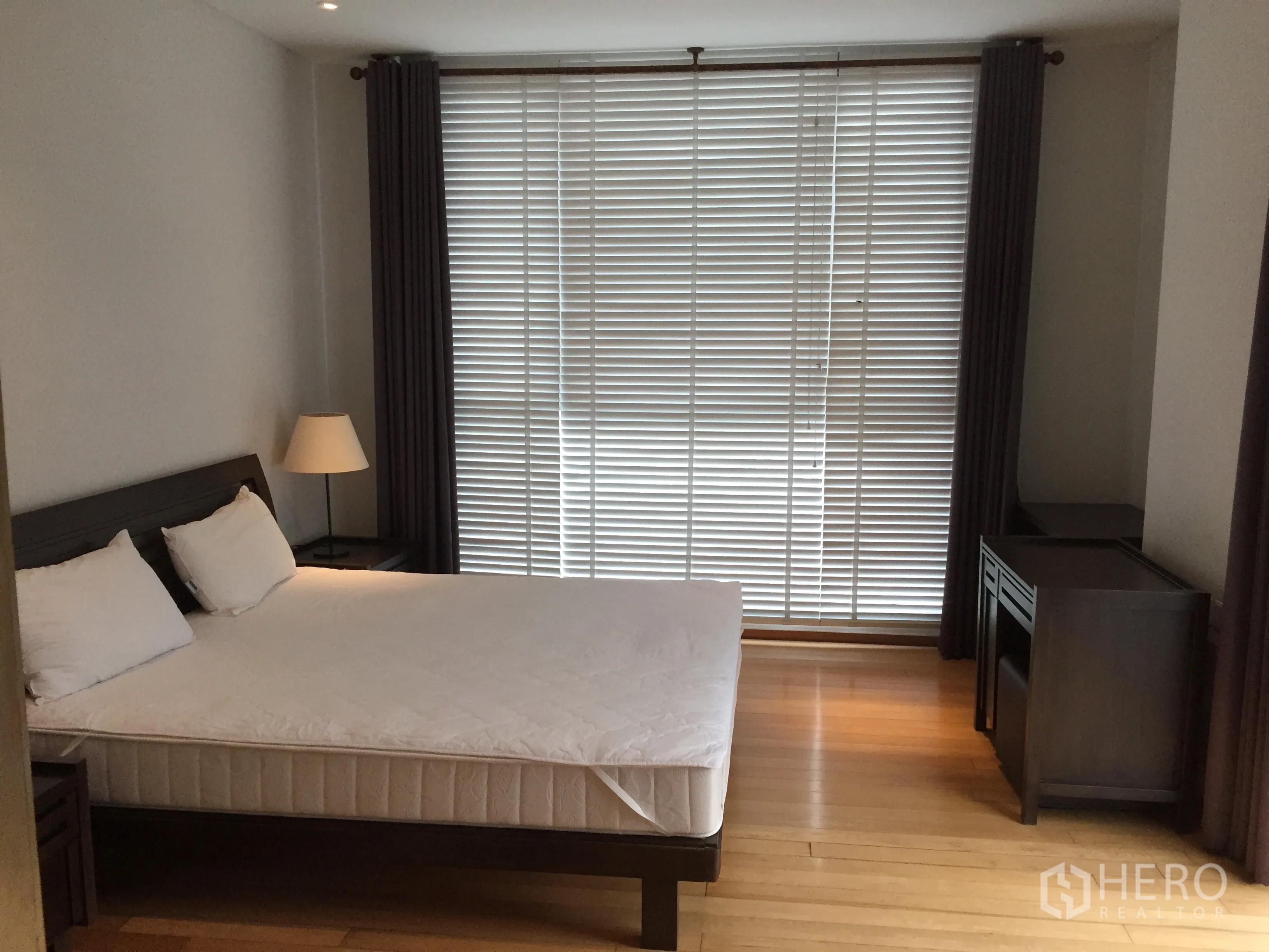 Condominium for rent or sale in Watthana, Bangkok - Bright master bedroom with large window blinds, wood floors and a queen-size bed.