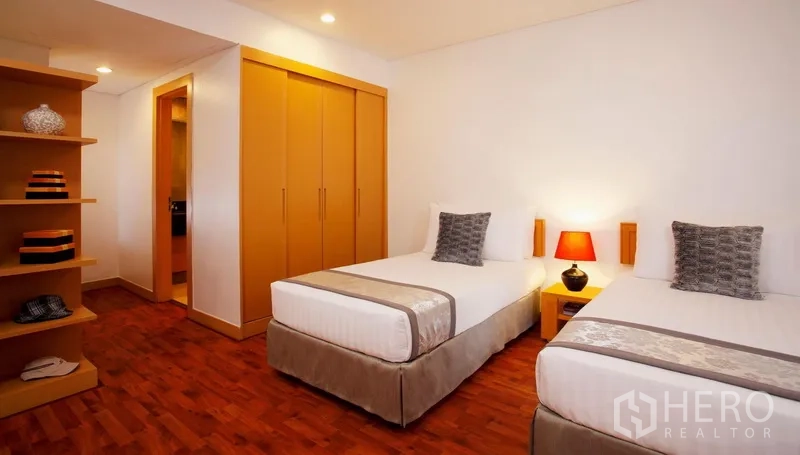 Condominium for rent in Watthana, Bangkok - Cozy twin bedroom with two single beds, built-in closet, open shelving and soft lighting.