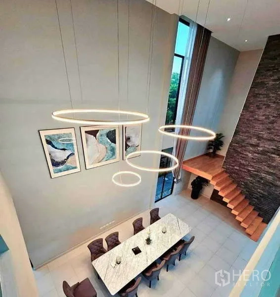 บ้าน ขายในKhlong Sam Wa, Bangkok - มุมมองจากด้านบนของโถงทานอาหาร พร้อมโคมไฟวงแหวนและหน้าต่างสูง