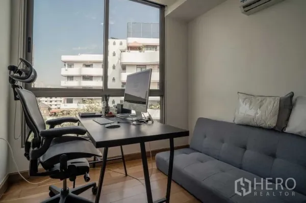 Condominium for sale in Watthana, Bangkok - Bright home office or guest room with desk, large window and city views.