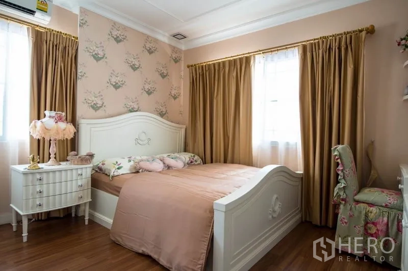 Detached House for sale in Bang Kapi, Bangkok - Charming second bedroom with floral wallpaper, white furniture and warm curtains.