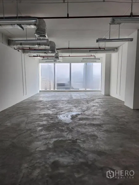 Office Space for rent in Sathon, Bangkok - Spacious workspace facing wide windows with panoramic city views and an exposed ceiling.