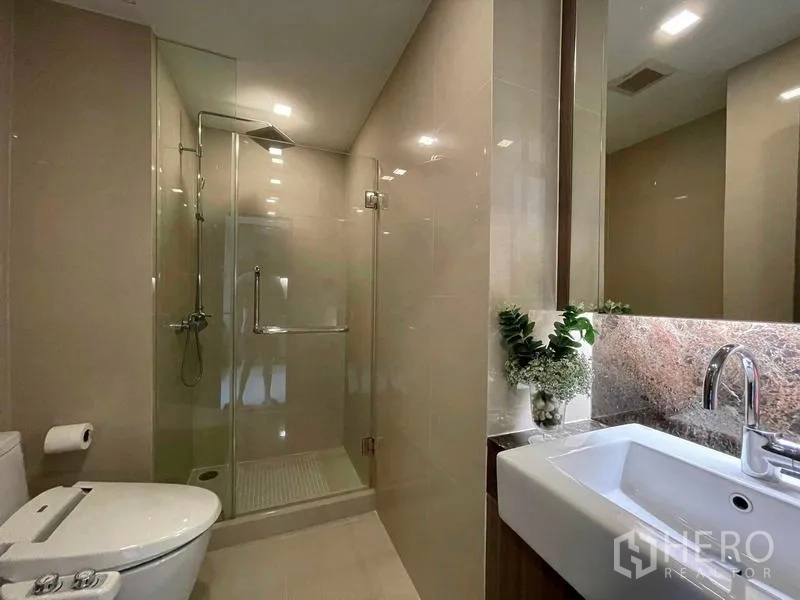 公寓 出租在Watthana, Bangkok - 现代卫浴，玻璃淋浴间、带灯洗手台与坐便器。