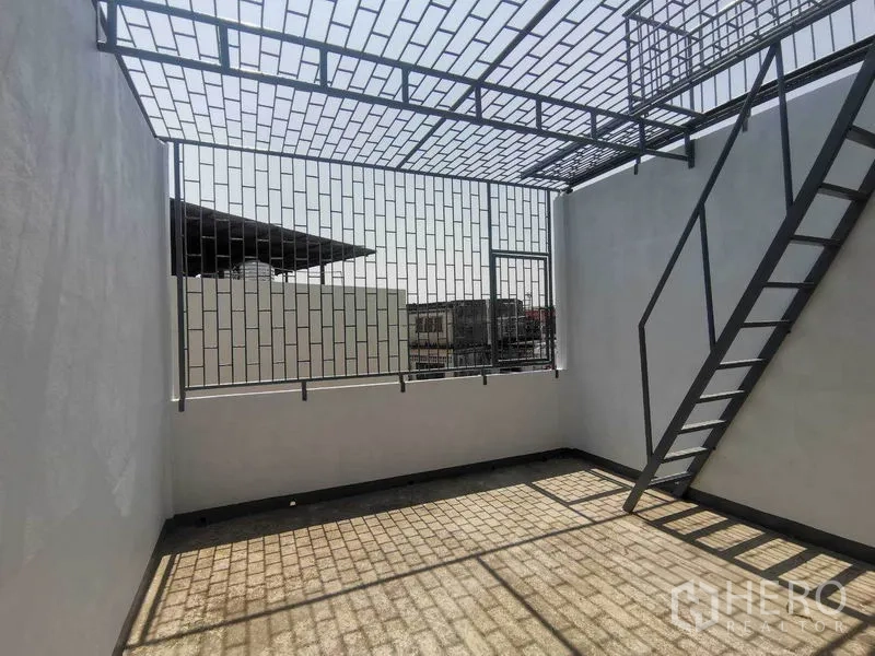 店屋 出租在Wang Thonglang, Bangkok - 屋顶露台，带金属防护棚与楼梯，可眺望城市。