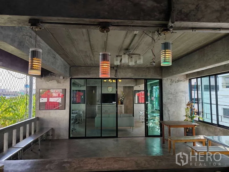 Warehouse for rent in Huai Khwang, Bangkok - Open terrace with pendant lights facing a lounge behind glass doors.