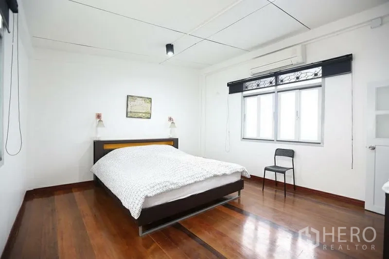Home Office for rent in Khlong Toei, Bangkok - Spacious bedroom with large windows, white walls and polished wooden flooring.
