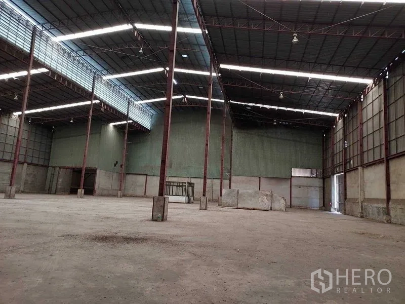 Warehouse for rent in Lat Lum Kaeo, Pathum Thani - Open interior bay facing a rear door and service area inside the warehouse.