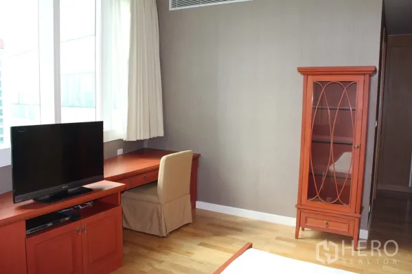 คอนโด ให้เช่าในKhlong Toei, Bangkok - มุมห้องนอนพร้อมโต๊ะทำงานริมหน้าต่างใหญ่ ชั้นวางทีวี และตู้โชว์กระจก