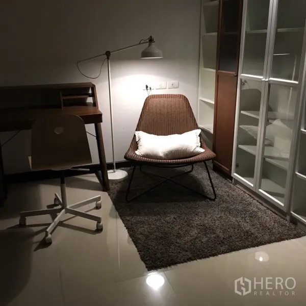 Condominium for rent in Watthana, Bangkok - Quiet study corner with desk, swivel chair, floor lamp, and shelving on glossy tile flooring.