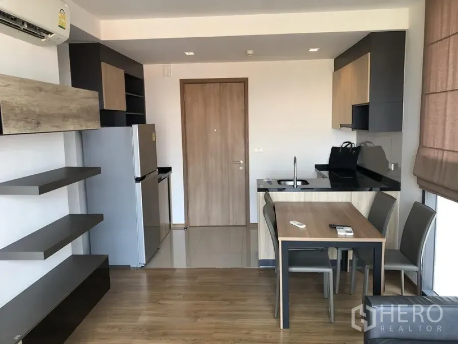 Condominium for rent in Watthana, Bangkok - Open-plan kitchen and dining area with wood cabinets, built-in shelves, and stainless fridge in a Bangkok condo.