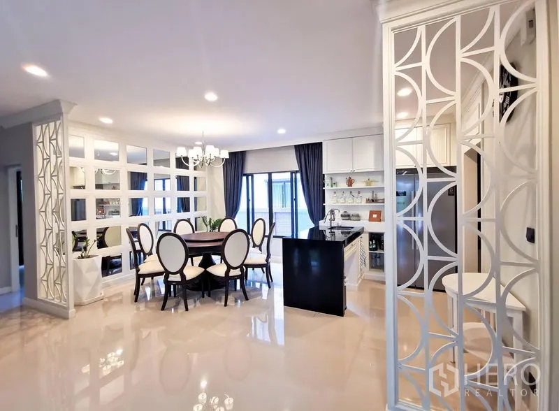 Detached House for rent or sale in Bang Kapi, Bangkok - Open-plan dining and kitchen with island, mirrored feature wall, decorative partitions, and glossy floors.