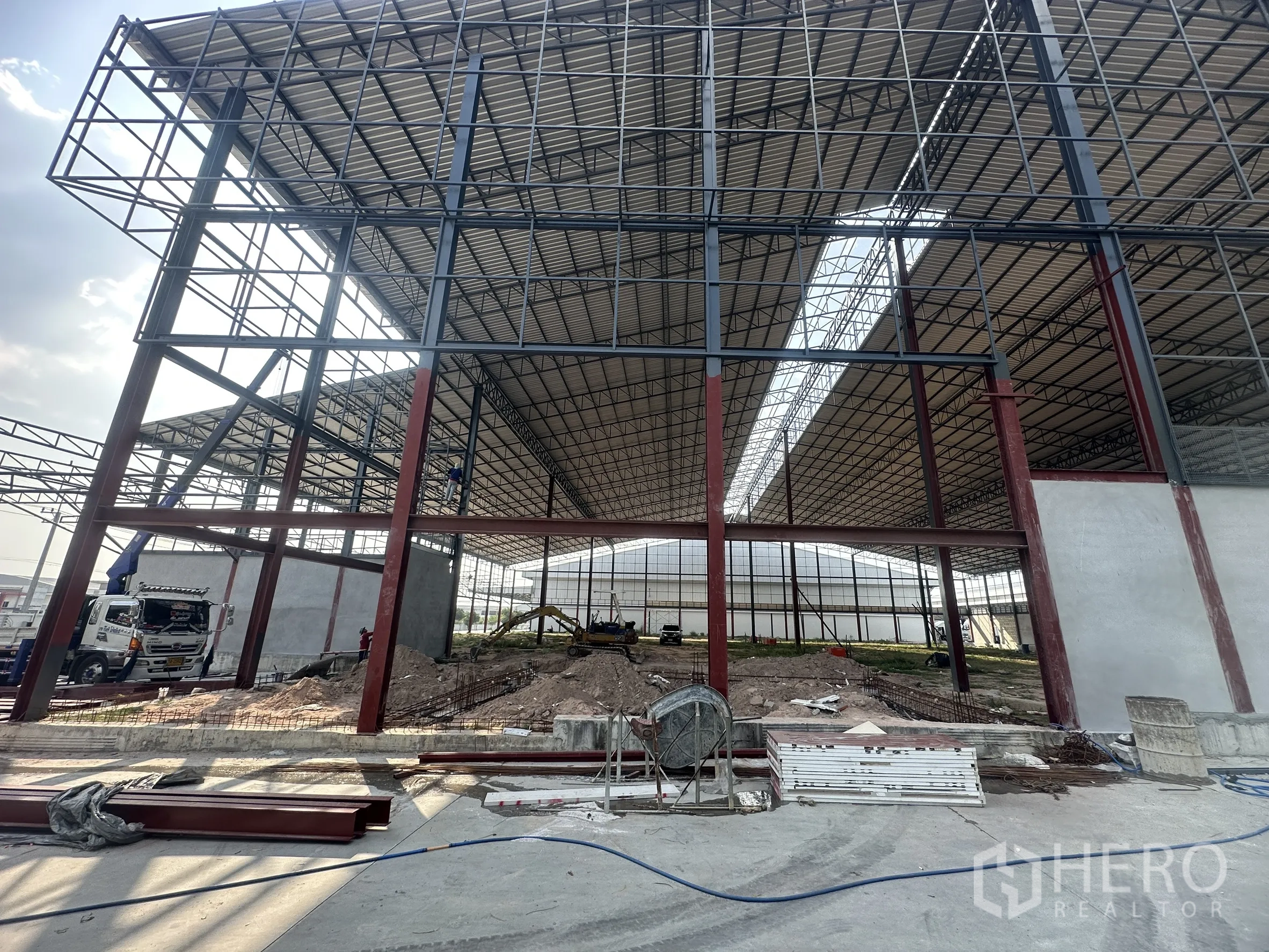 Factory for rent in Si Racha, Chon Buri - High steel truss roof and red columns forming a spacious warehouse bay under construction.