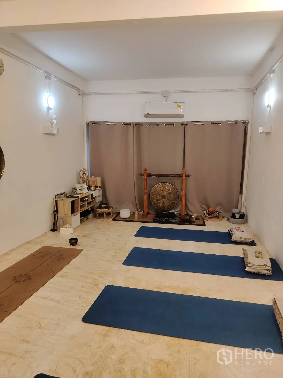 店屋 出租在Watthana, Bangkok - 明亮的工作室房间，铺有瑜伽垫并摆放锣，浅色墙面与窗帘，配空调。