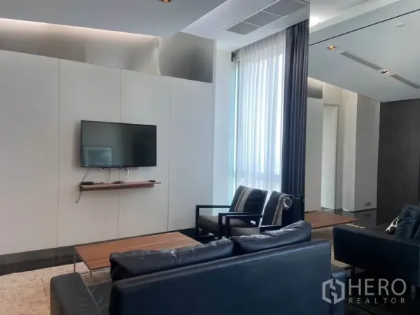 公寓 出租在Sathon, Bangkok - 极简起居区，墙面挂电视，窗帘与成套座椅。