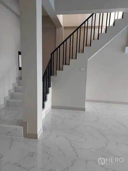 Shophouse for rent in Bang Kapi, Bangkok - Staircase with black metal railing dividing an open workspace with white tiles.