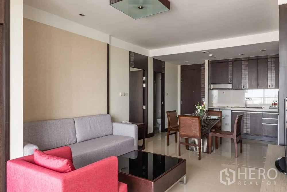 อพาร์ทเมนท์ ให้เช่าในKhlong Toei, Bangkok - ห้องนั่งเล่นโอเพ่นแพลนพร้อมโซฟา ชุดทานอาหาร และครัวบิลท์อินตู้สีเข้ม