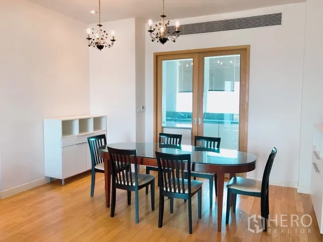 Condominium for rent or sale in Khlong Toei, Bangkok - Dining room with oval glass table, six chairs, pendant chandeliers and sliding glass doors.
