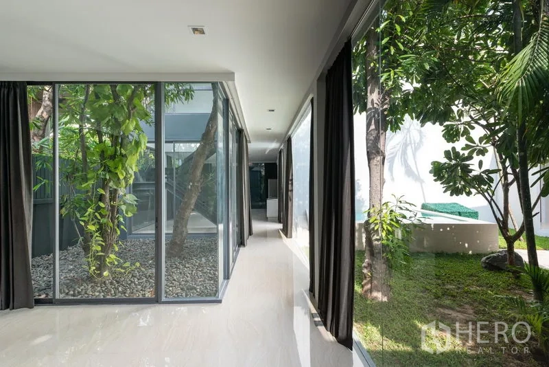 Home Office for rent in Khlong Toei, Bangkok - Sunlit hallway with floor-to-ceiling windows around an internal courtyard with trees.