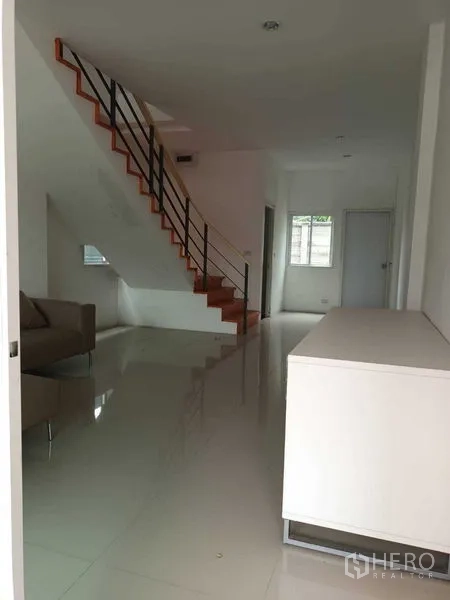 Shophouse for sale in Bueng Kum, Bangkok - Ground-floor hall with staircase, sofa and a built-in counter facing the front glass door.
