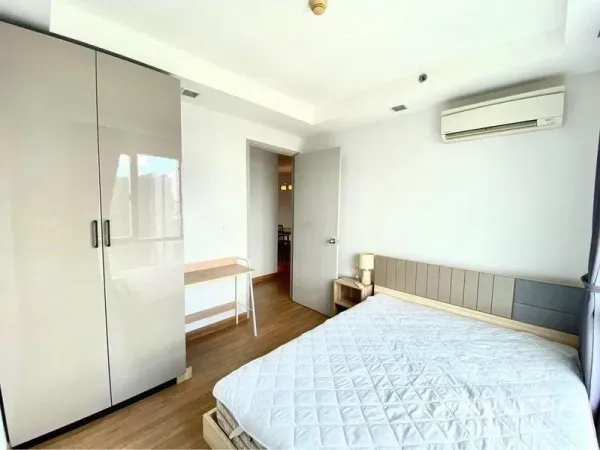Condominium for rent in Huai Khwang, Bangkok - Bright secondary bedroom with wardrobe, desk and air conditioning.