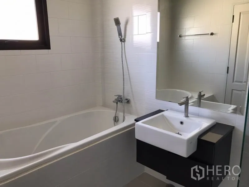 Detached House for rent in Bang Phli, Samut Prakan - Bathroom with bathtub, handheld shower, large mirror and window.