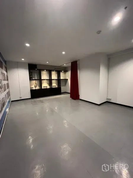 零售空间 出租在Watthana, Bangkok - 开放式零售室内，灰色地面、筒灯照明与内置展示柜。