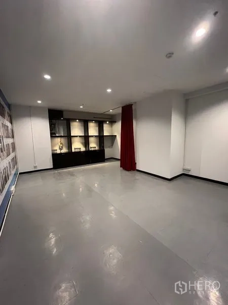 零售空间 出租在Watthana, Bangkok - 开放式零售室内，灰色地面、筒灯照明与内置展示柜。