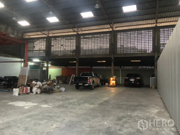 Warehouse for rent in Min Buri, Bangkok - Spacious warehouse interior with high steel roof, skylights, ventilated block walls and concrete floor with truck parking.