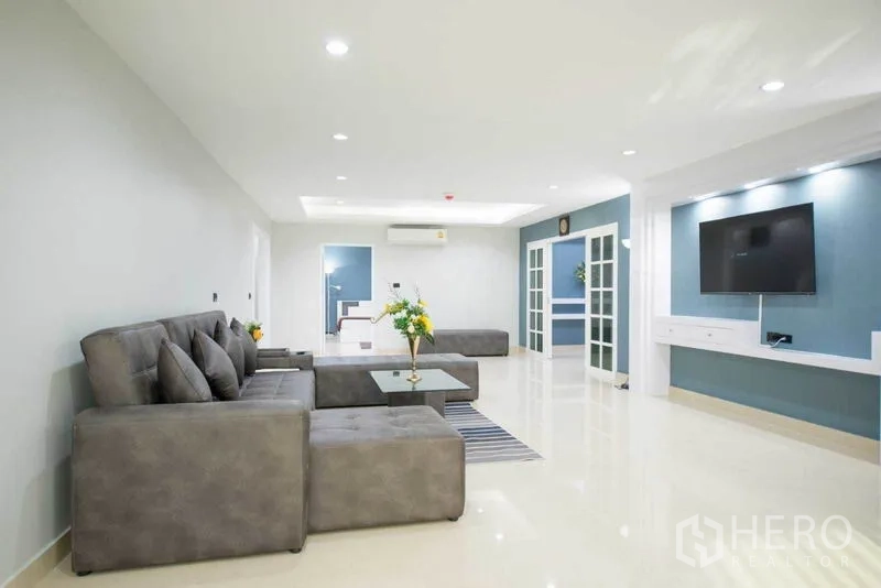 公寓 出租在Khlong Toei, Bangkok - 超大客厅，L 型沙发、电视墙柜、推拉门与嵌灯照明。