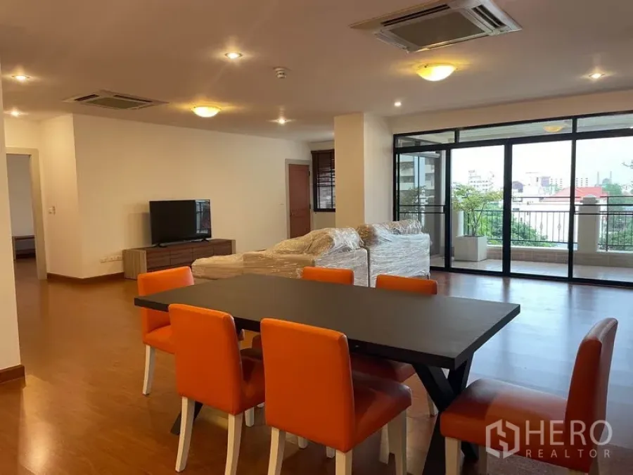 公寓 出租在Watthana, Bangkok - 开放式客餐厅，橙色餐椅、木地板，落地滑门通往阳台的Ekkamai公寓。